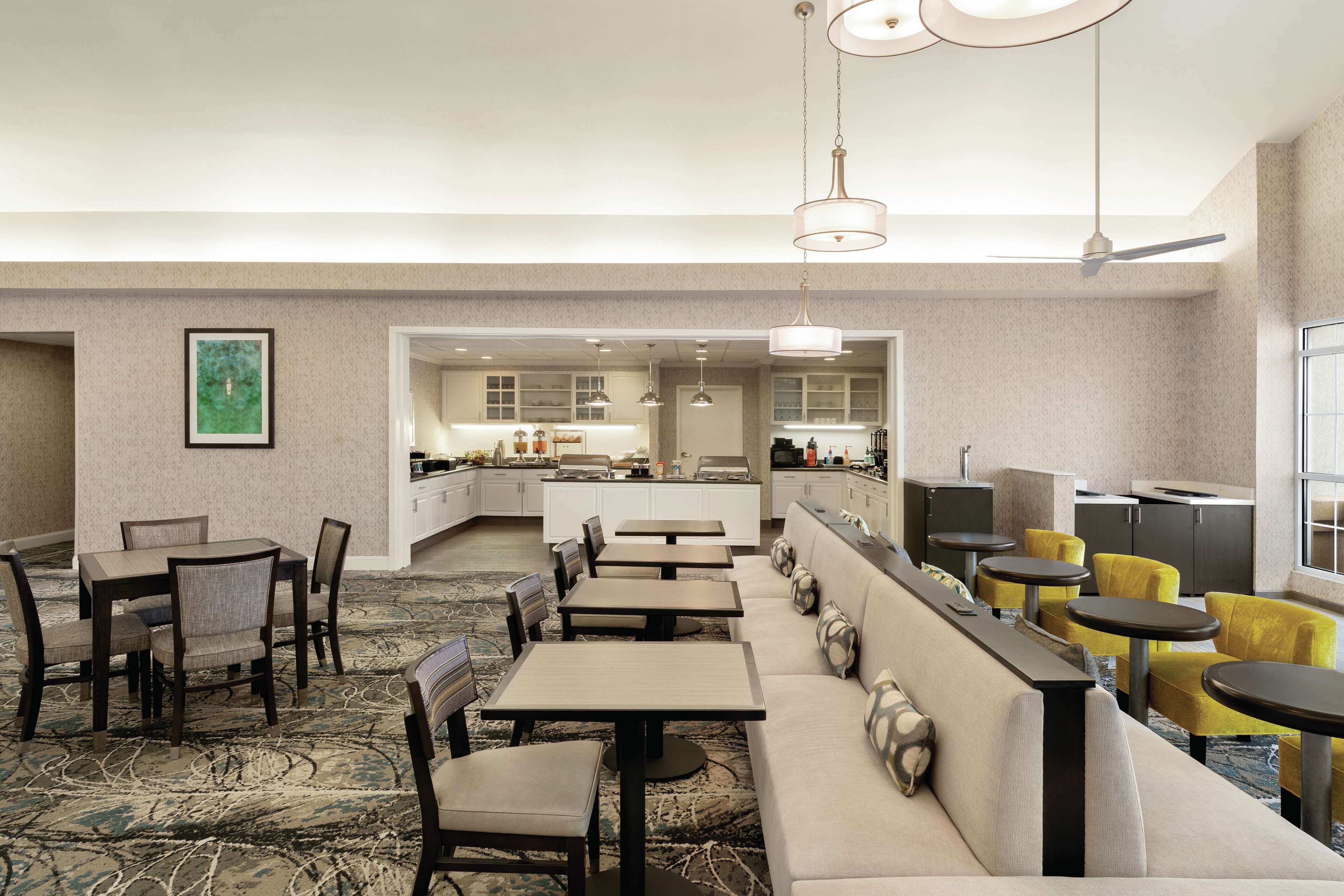 Un hall d'hôtel comprenant un espace repas, un bar et une cuisine en arrière-plan.