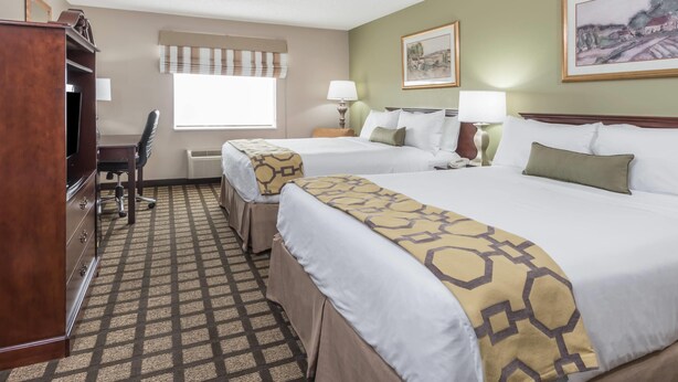 A hotel room with two beds, a desk, a chair, a wardrobe, and a window with a view. - Baymont by Wyndham Fulton (Fulton)