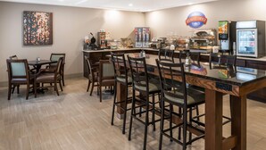 A breakfast area with a counter, seating, and a refrigerator. - Baymont by Wyndham Fulton (Fulton)
