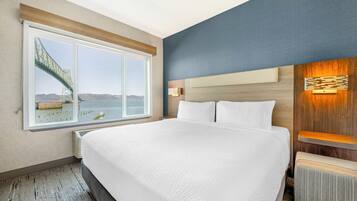 Quarto de hotel com uma cama grande, vista para uma ponte e cabeceira de madeira.