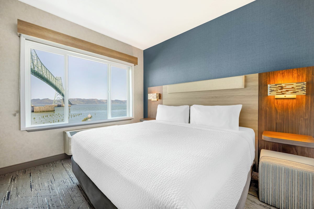 A hotel room with a large bed, a view of a bridge, and a wooden headboard.