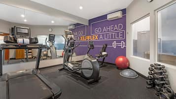 Ett gym med löpband, crosstrainers, en motionscykel, en röd träningsboll och ett ställ med hantlar.