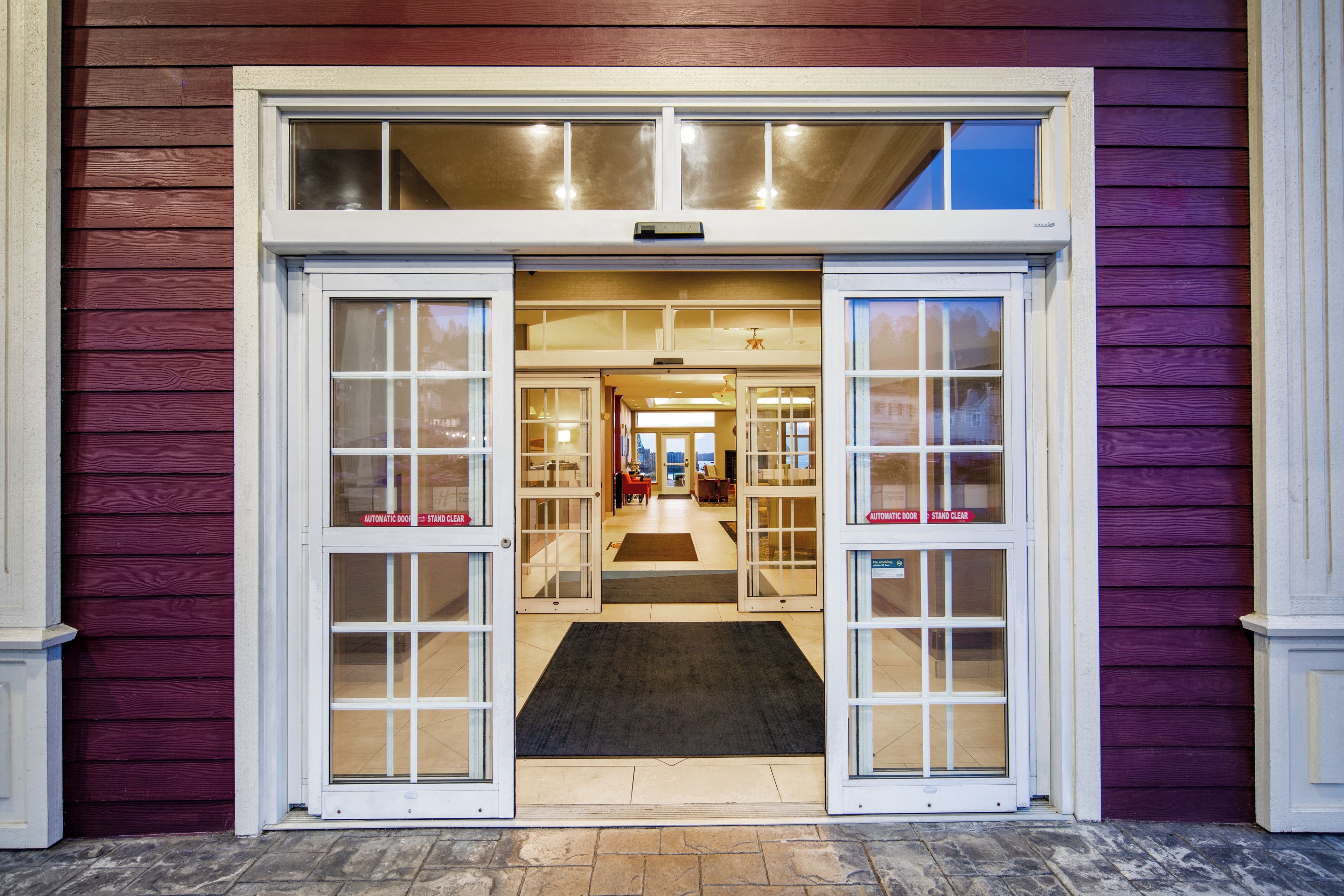 A hotel entrance with a double door, a visible interior hallway, and a clear view of the interior through the glass doors.