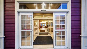 A hotel entrance with a double door, a visible interior hallway, and a clear view of the interior through the glass doors.