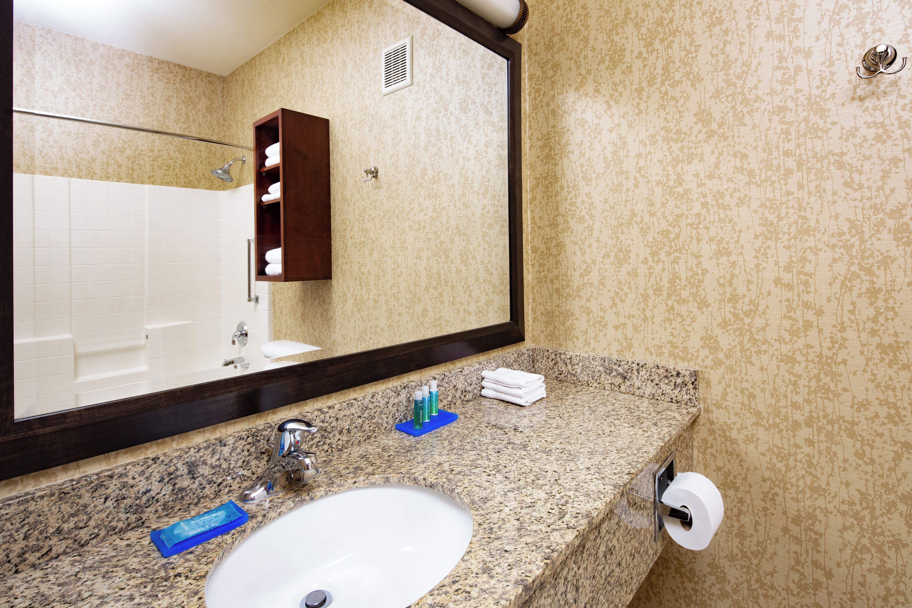 Une salle de bain équipée d’un lavabo, d’un miroir, d’un porte-serviettes et d’articles de toilette.