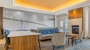 A modern hotel lobby with a large dining table, seating area, and a fireplace. - Holiday Inn Express & Suites Astoria by IHG (Astoria)