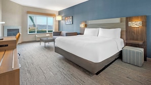 A modern hotel room with a large bed, a desk, a chair, and a window with a view of the mountains. - Holiday Inn Express & Suites Astoria by IHG (Astoria)