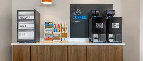 A counter with a coffee station, labeled with 'YOGURT,' 'EGGS,' and 'MILK.' There are coffee machines and a sign that says 'MUST. HAVE. COFFEE.'