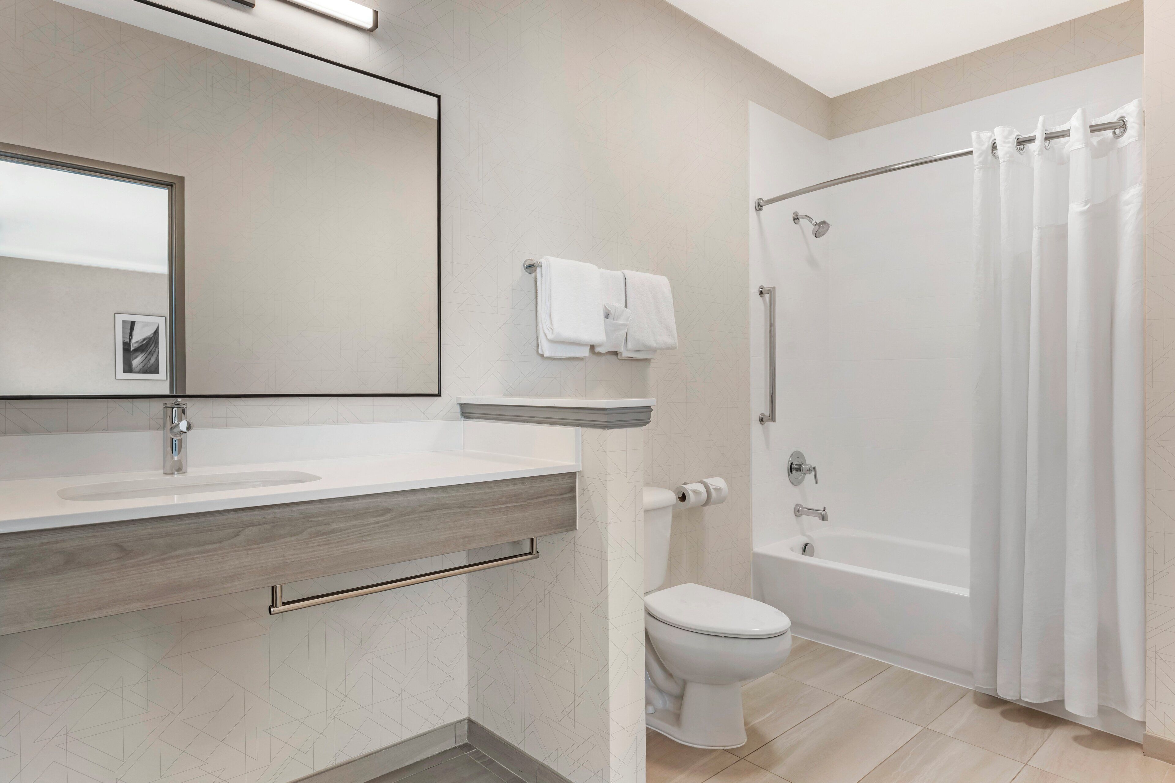 A modern bathroom with a large mirror, two sinks, a toilet, and a shower with a curtain.
