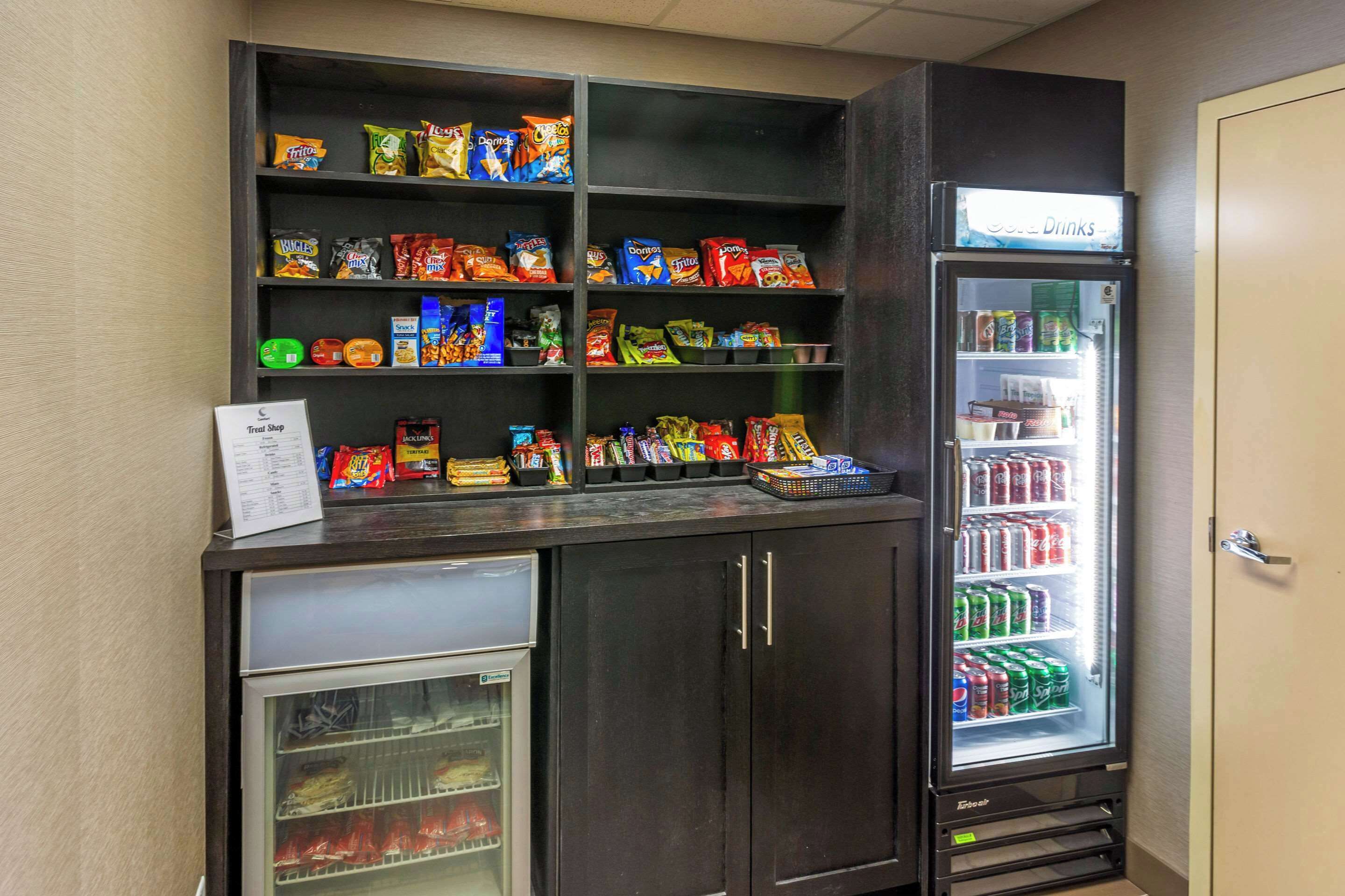 A vending machine stocked with snacks and drinks, a refrigerated display case, and a small refrigerator with beverages.