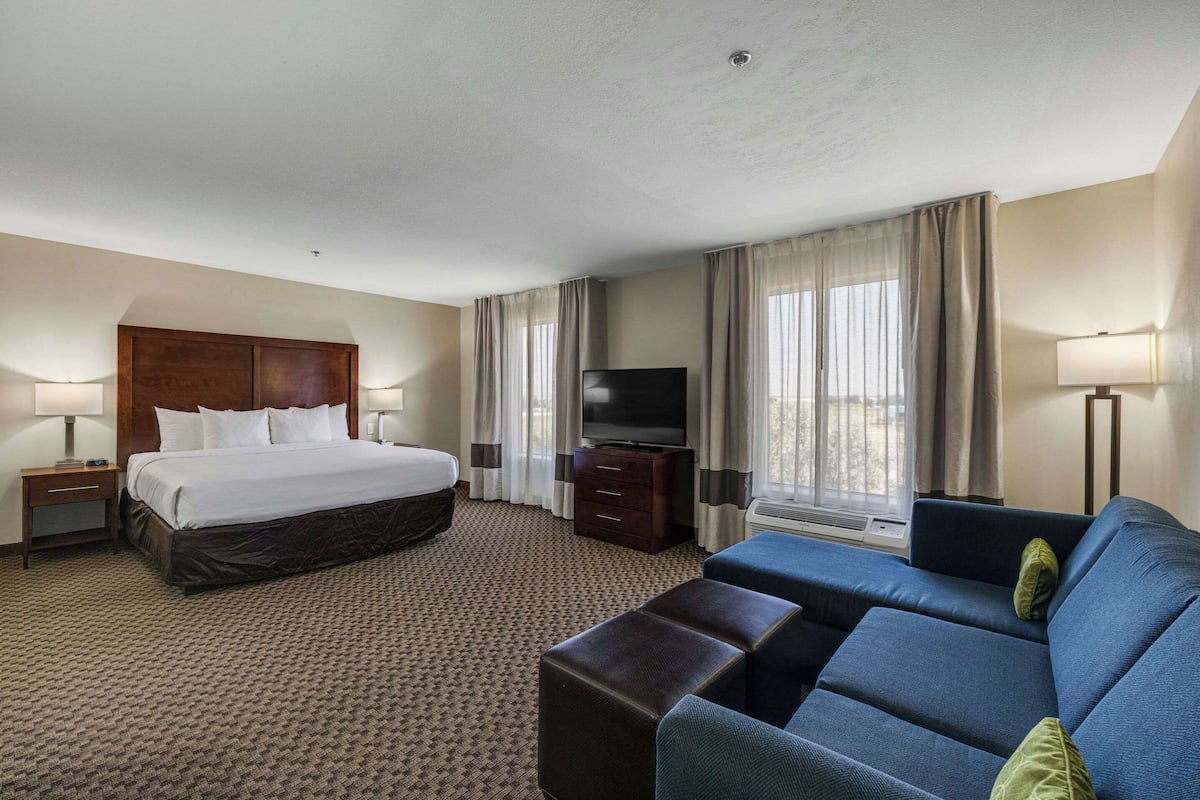 Ein Hotelzimmer mit einem großen Bett, einem Flachbildfernseher, einer Couch und einem Schreibtisch.