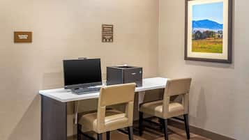 Un centro de negocios con un escritorio, computadora y dos sillas.