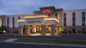 Een Hampton Inn & Suites met een moderne gevel, een ruime entree en een goed verlichte buitenkant.