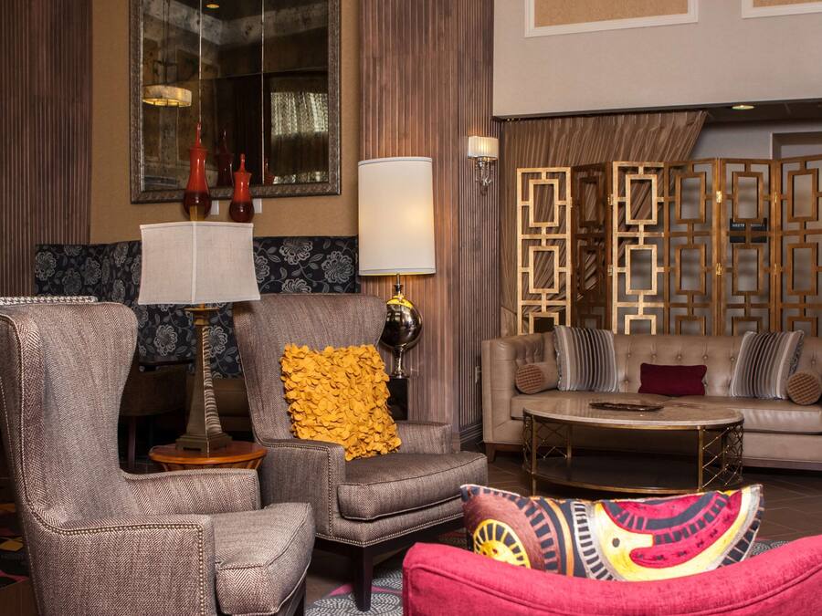 Een ruime zithoek met een bank, fauteuils, een salontafel en een decoratieve lamp.