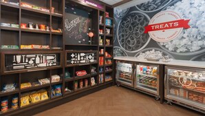 Een afdeling voor snacks en kleine benodigdheden met planken vol diverse verpakte producten en een koelvitrine.