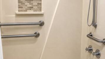 Un baño con bañera, barras de apoyo, ducha y toallero.