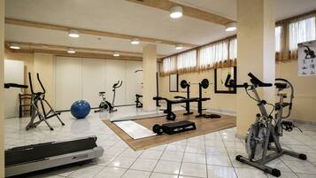 Una palestra con diverse attrezzature per allenamento, tra cui tapis roulant, cyclette e macchinari per pesi.