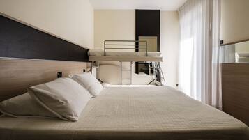 A hotel room with a bunk bed, a single bed, and a large window with curtains.