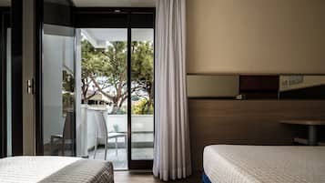 Habitación de hotel con dos camas, una puerta corrediza de vidrio a un área exterior y un cabecero de madera.