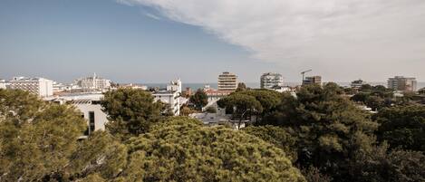 A coastal cityscape with modern buildings, dense greenery, and a clear sky.