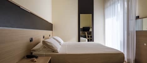 Una habitación de hotel con una cama, una mesita de noche y un espejo.