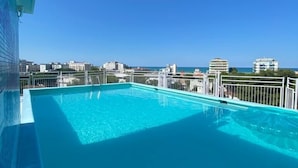 A rooftop pool with a clear view of the city skyline and the sea. - Hotel Augustus (Riccione)