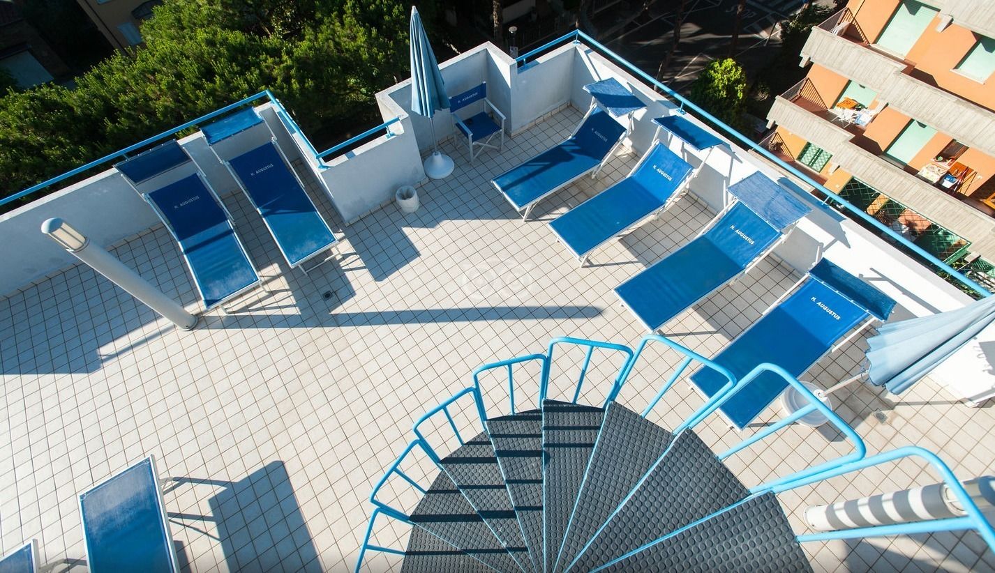 A rooftop pool area with multiple sun loungers and a staircase leading to an upper level.