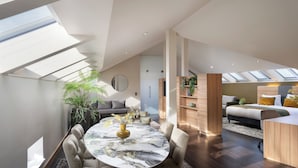 A modern loft-style living space with a dining area, a bedroom, and a kitchen. -  Leonardo Boutique Hotel Salzburg Gablerbräu (Salzburg)