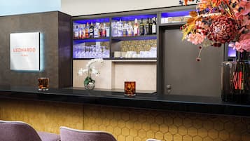 Zona de bar con un letrero que dice 'LEONARDO Hotels' y una variedad de botellas de licor.