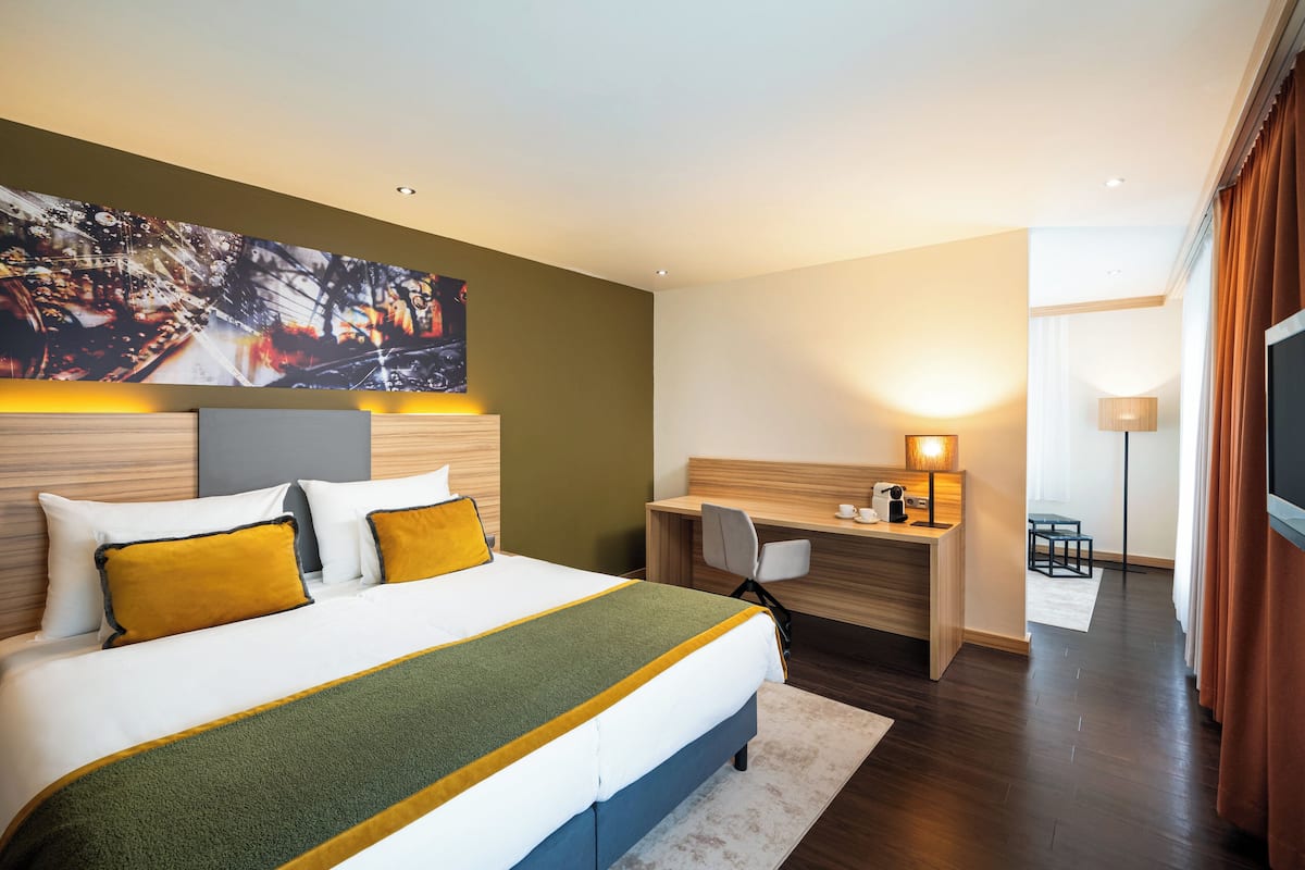 A modern hotel room with a large bed, a desk, and a TV.