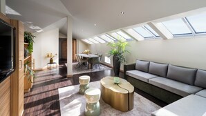A modern living room with a sofa, coffee table, and dining area. -  Leonardo Boutique Hotel Salzburg Gablerbräu (Salzburg)