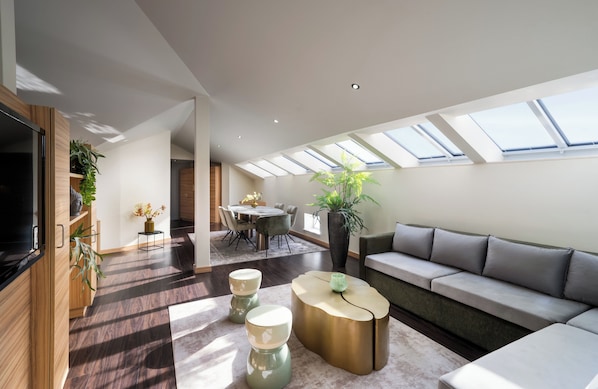 A modern living room with a sofa, coffee table, and dining area.