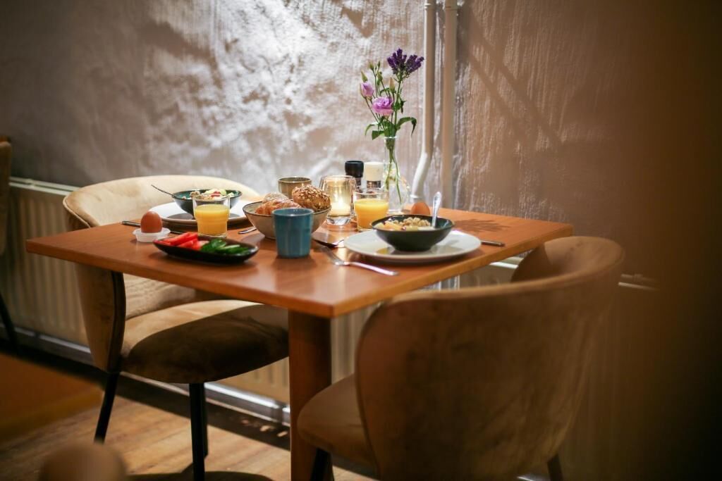Una mesa de desayuno con diversos alimentos y un jarrón de flores.