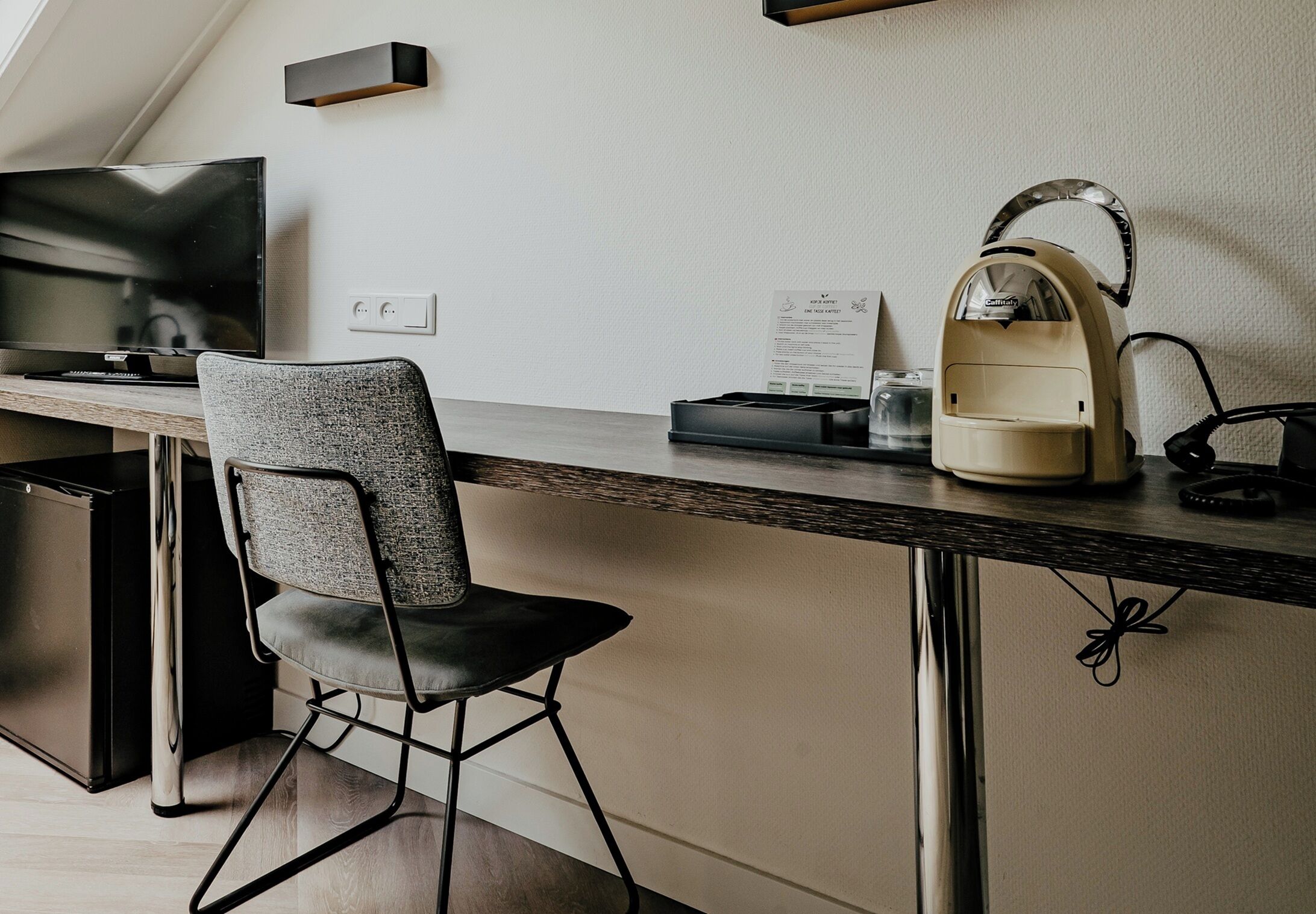 Un espacio de oficina moderno con escritorio, silla y cafetera.