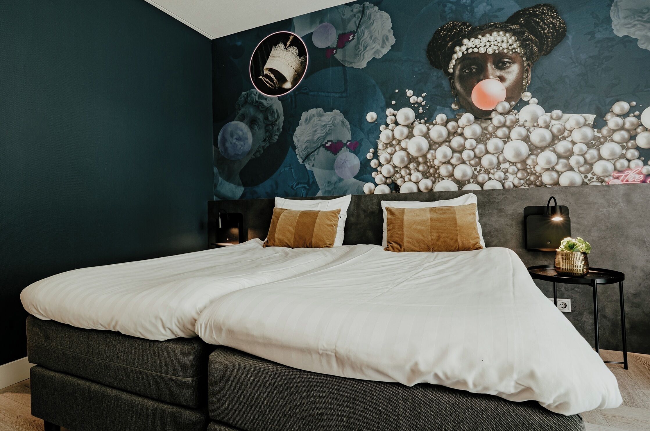 A modern bedroom with a large bed, dark walls, and a mural on the wall.