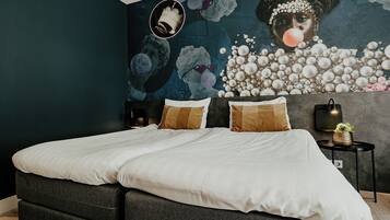 A modern bedroom with a large bed, dark walls, and a mural on the wall.