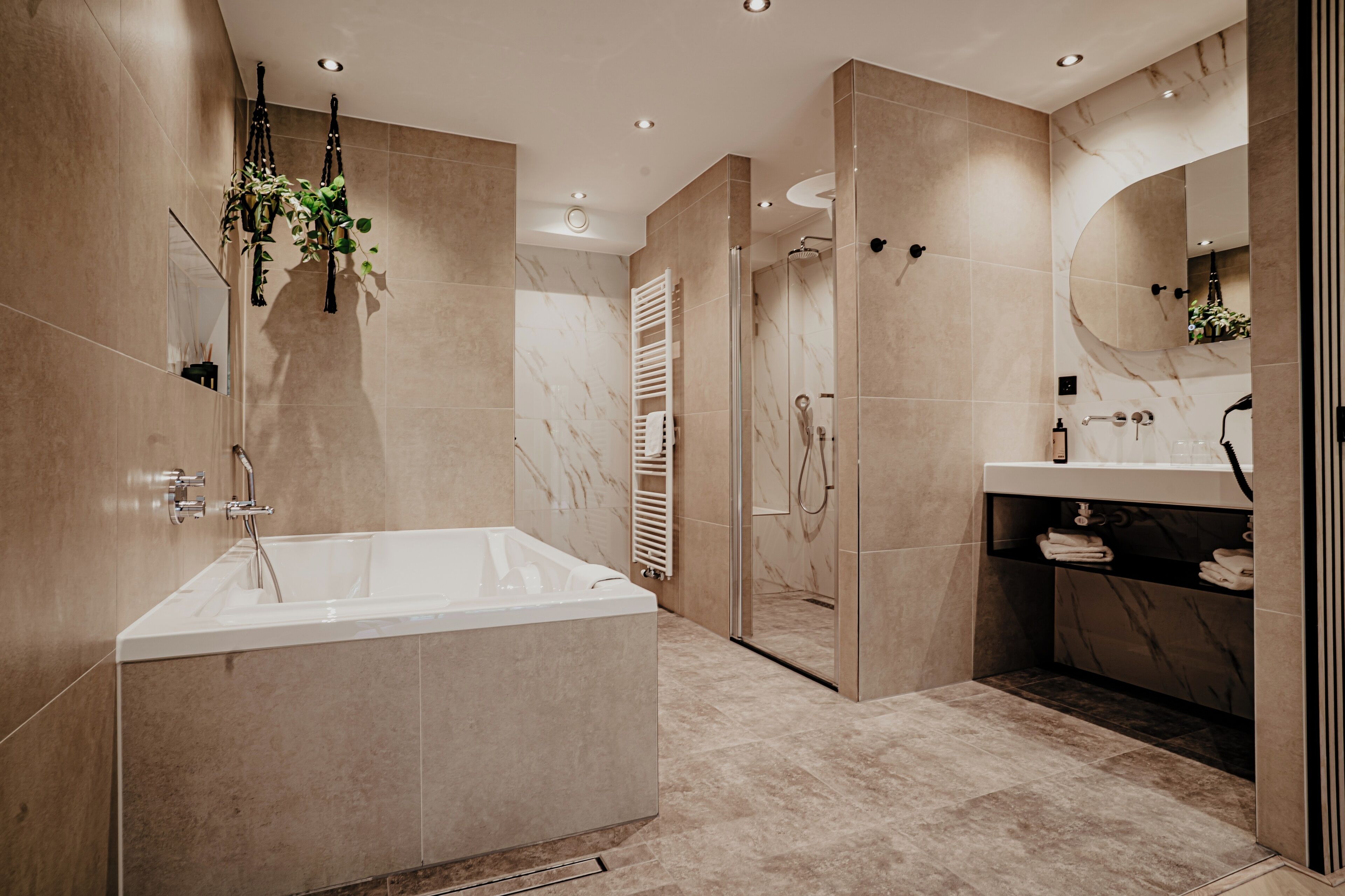 Une salle de bain moderne dotée d’une grande baignoire, d’une douche à l’italienne et d’un meuble-lavabo avec un miroir.