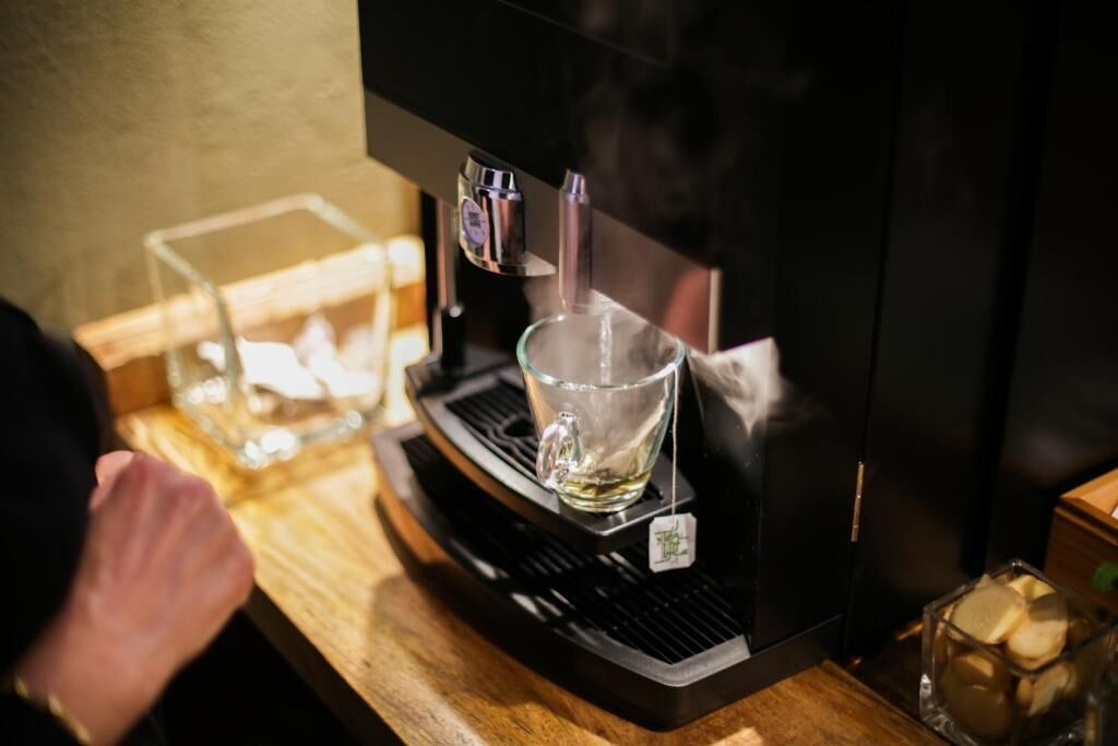 A coffee machine with a glass cup on its drip tray.