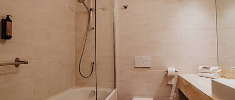 A modern bathroom with a bathtub, toilet, and shower.