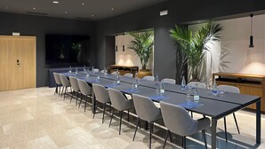 A modern conference room with a long table, chairs, water bottles, and potted plants. - Hotel SB Madrid Norte (San Sebastian de los Reyes)