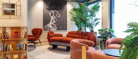 Un interior moderno con un sofá, sillones, una estantería y un ventanal grande.