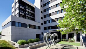 A modern building with a courtyard, featuring a unique sculpture and a clear sky. - Hotel SB Madrid Norte (San Sebastian de los Reyes)