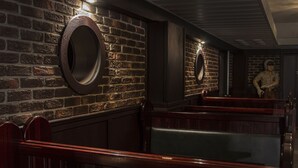 A dimly lit room with brick walls, wooden benches, and circular mirrors on the walls. - Hotell Stinsen (Hallsberg)