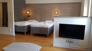 A modern hotel room with two beds, a flat-screen TV, and a small table. - Hotell Stinsen (Hallsberg)