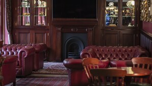 A traditional living room with a fireplace, leather sofas, and a television. - Hotell Stinsen (Hallsberg)