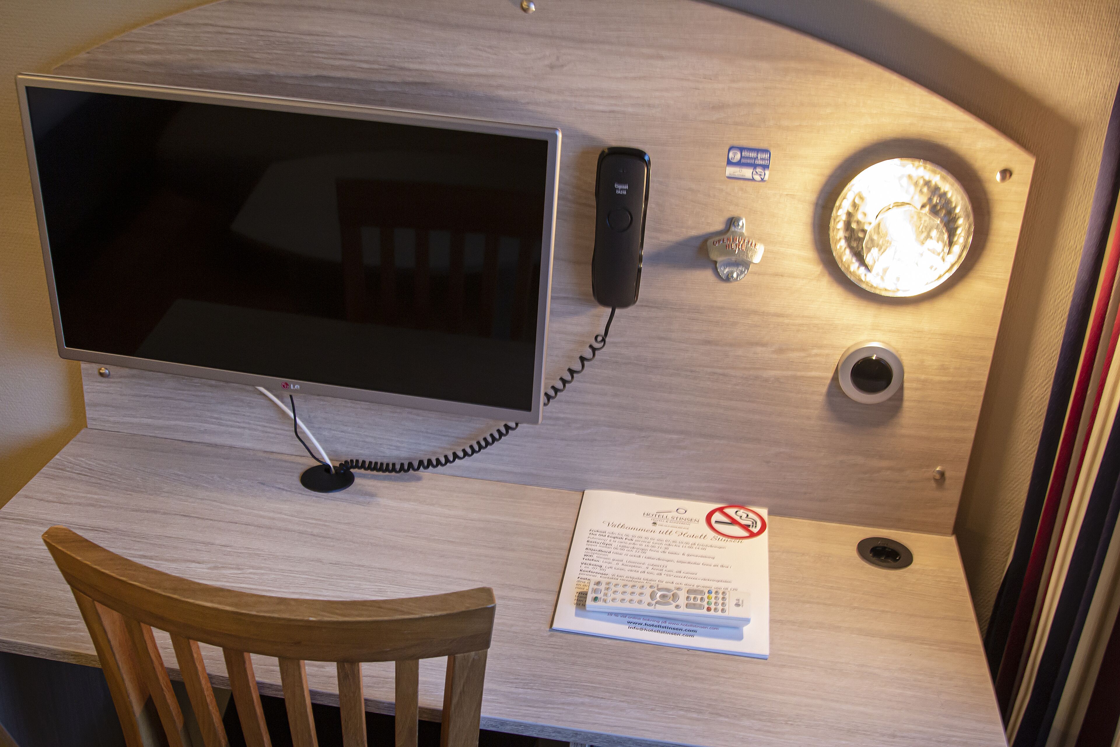 Un bureau en bois, équipé d’un écran plat, d’un téléphone et d’un luminaire.