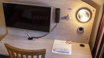 Un bureau en bois, équipé d’un écran plat, d’un téléphone et d’un luminaire.