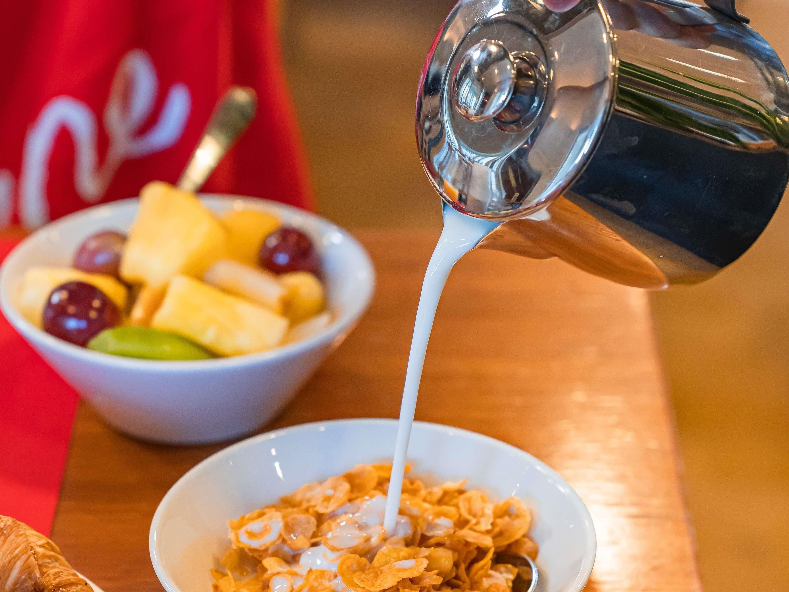 A bowl of cereal with milk being poured into it.
