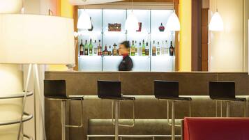 Zona de bar con un cantinero, taburetes y una exhibición de botellas de licores.