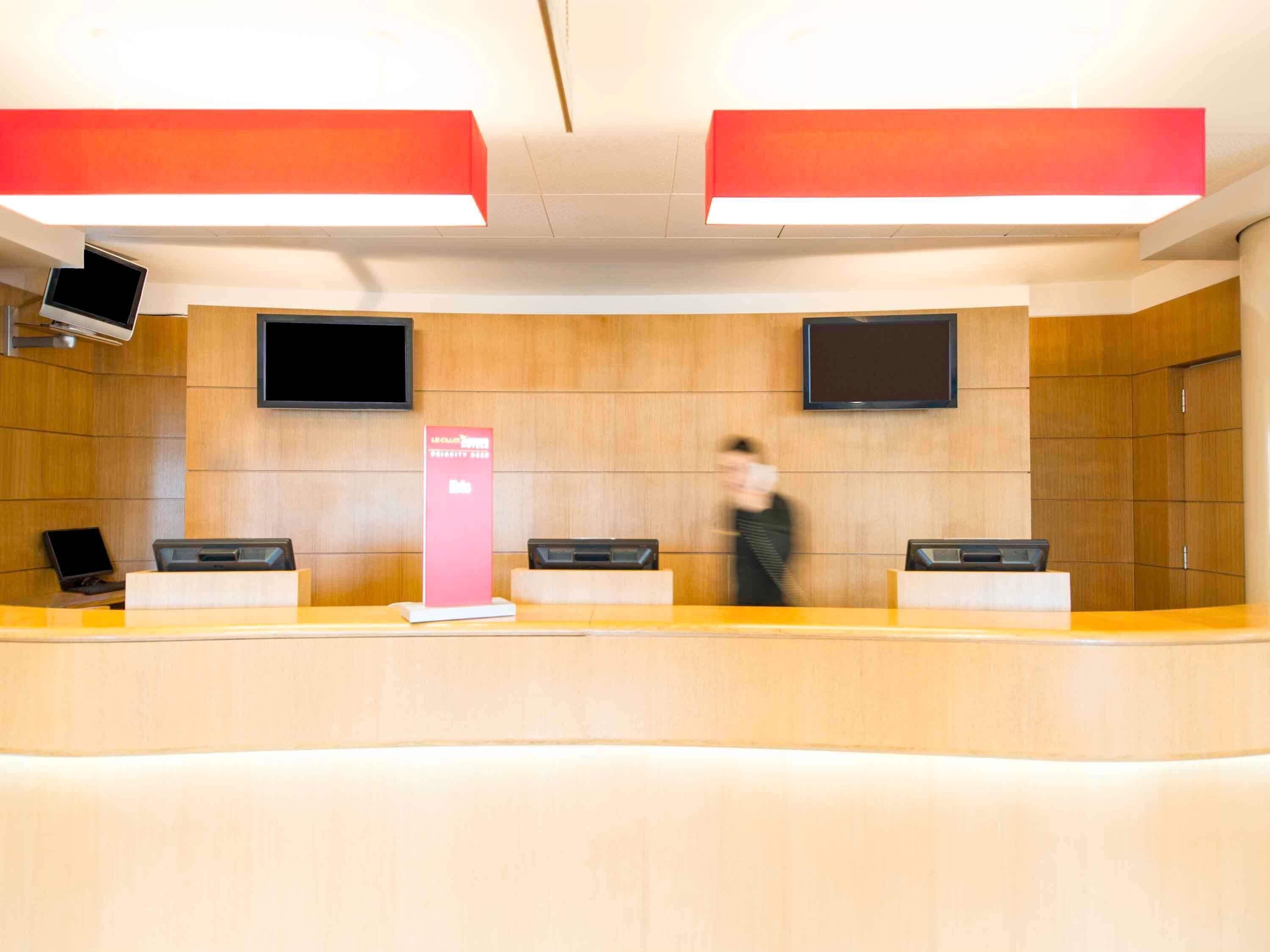 Un comptoir d’accueil équipé d’un téléviseur à écran plat, d’un kiosque numérique et d’un panneau d’affichage.